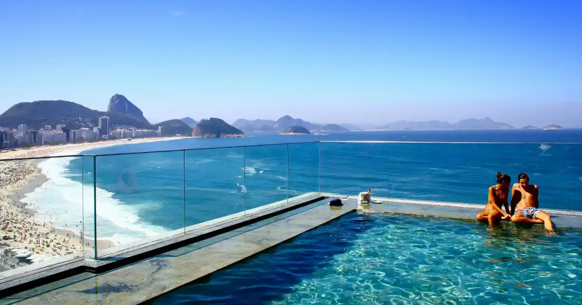 Um casal dentro de uma piscina com vista para o Pão de Açucar no Rio de Janeiro